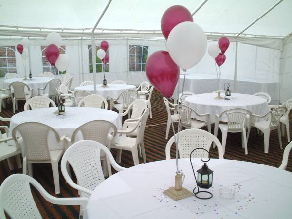 Covered tables and chair with balloons inside a marquee